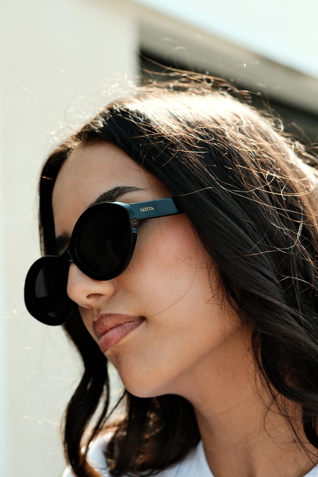 Gros plan sur des lunettes de soleil rondes noires Gotta portées par une femme